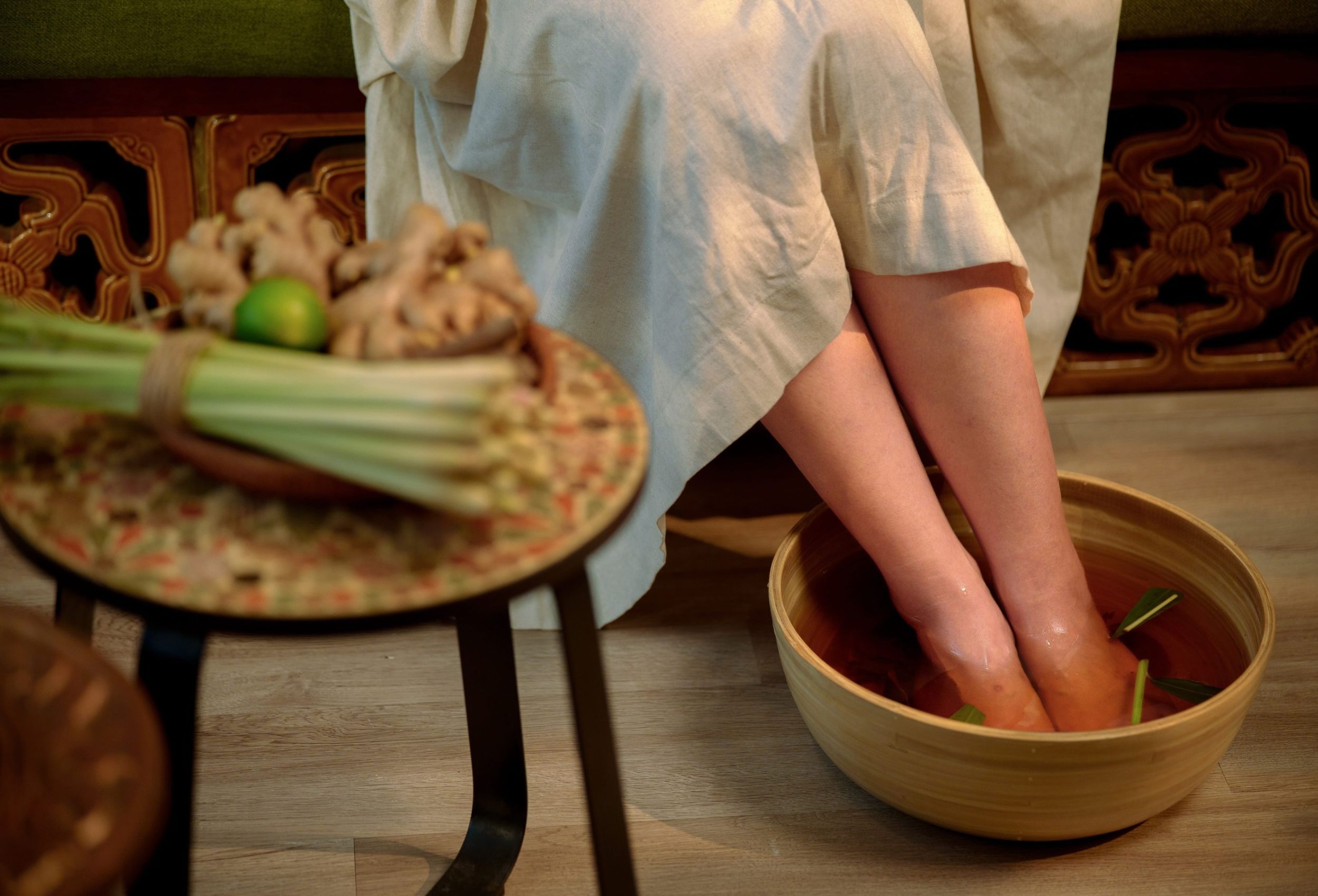 Ngâm chân với nước ấm thảo mộc tự nhiên trong bồn gỗ mộc mạc trước buổi massage