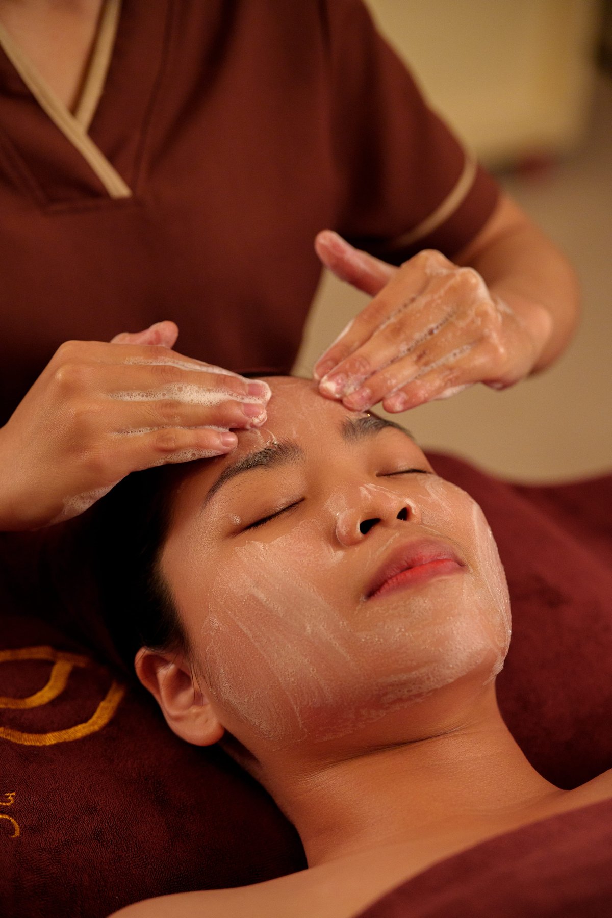 Kỹ thuật viên thực hiện bước tẩy tế bào chết dạng gel sinh học nhẹ nhàng trên da mặt khách hàng tại Tỉnh Thức Spa